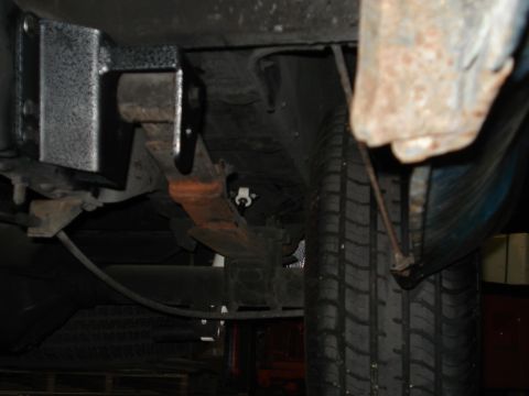 1979 Chevrolet C/K Pickup - Underside view of a vehicle's suspension system, focusing on a leaf spring and tire.