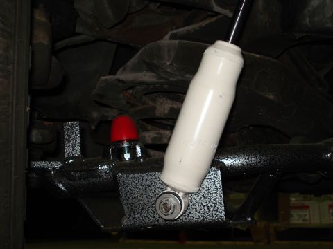 1979 Chevrolet C/K Pickup - Close-up view of the undercarriage, showing a white shock absorber and a red cap on a bolt.