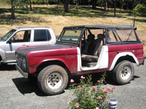 1968 Ford Bronco - A classic red Ford Bronco with white doors sits parked next to a modern SUV.