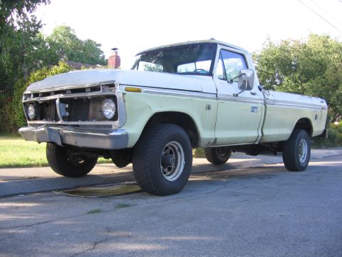 1989 Ford Bronco - This 1976 Ford F-150 pickup truck is shown from the front-left, revealing its two-tone paint scheme and missing grille components.