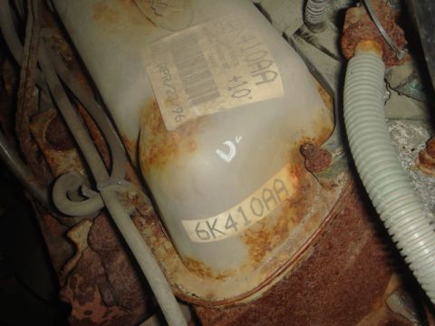 1996 Ford Bronco - A close-up view of a rusty engine component with a date and part number visible on a label.