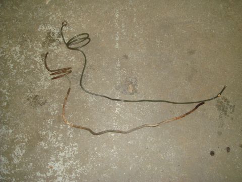 1996 Ford Bronco - A detached brake line, showing signs of rust and wear, lies on a concrete surface.