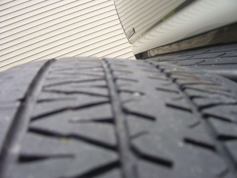 2004 Chevrolet Silverado 1500 - A close-up view of a vehicle's tire, with the side of the vehicle and siding in the background. Text is visible at the bottom right.