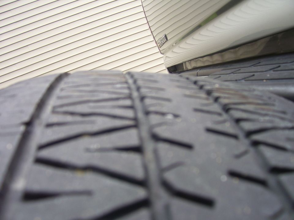 Extreme close-up of all-terrain tire tread beside vehicle body and siding