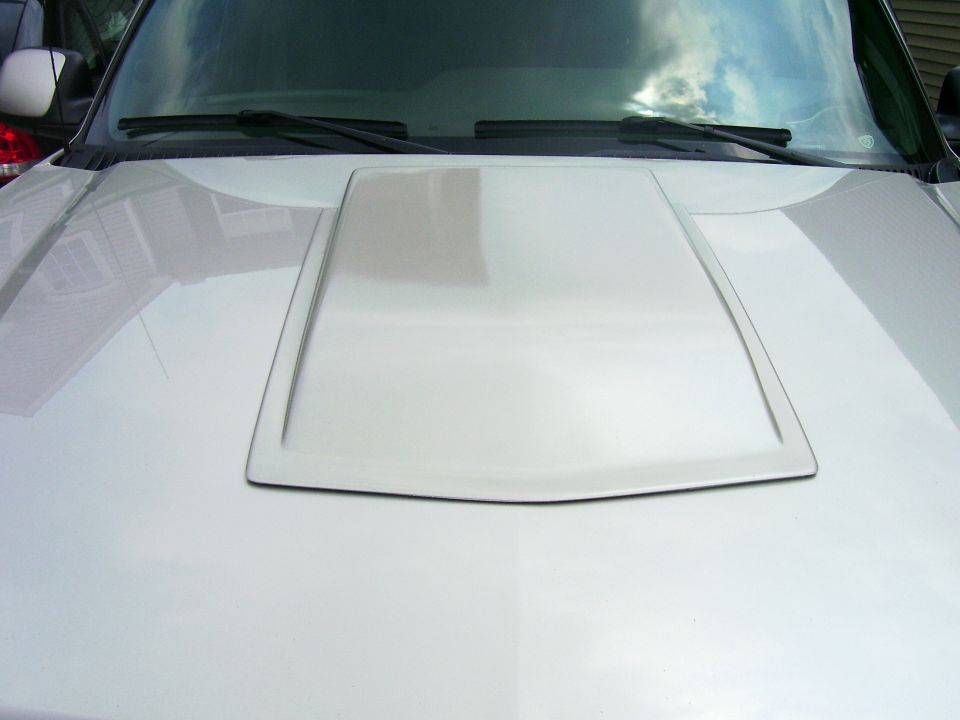 Body-color cowl hood scoop on the white hood of a pickup truck