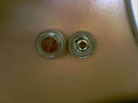 2001 Ford Crown Victoria - Close-up of two clear plastic caps, one containing an Energizer battery and the other a bolt.