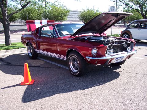 1972 Ford Ranchero - A red 1968 Ford Mustang GT, identifiable by its body style and racing stripes, is displayed with its hood open, parked next to another vehi…