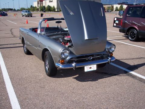 1972 Ford Ranchero - Silver convertible parked in a lot with hood open, engine visible.