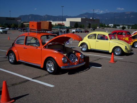 1972 Ford Ranchero - Several Volkswagen Beetles are parked in a lot, with one orange Beetle having its hood open.