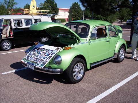 1972 Ford Ranchero - A green 1972 Volkswagen Beetle is displayed with its hood open, showing a photo collage on the front. Another vehicle is parked behind.