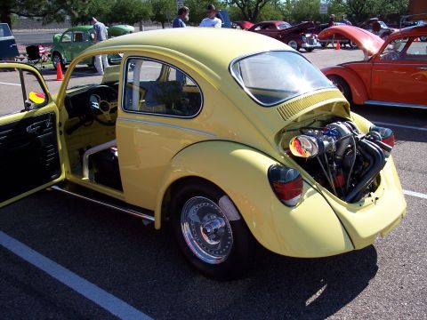 1972 Ford Ranchero - Customized yellow VW Beetle with engine exposed, parked at a car show with other vehicles present.