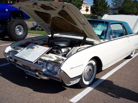 1972 Ford Ranchero - A white 1961 Ford Thunderbird is displayed with its hood open, next to a blue monster truck.