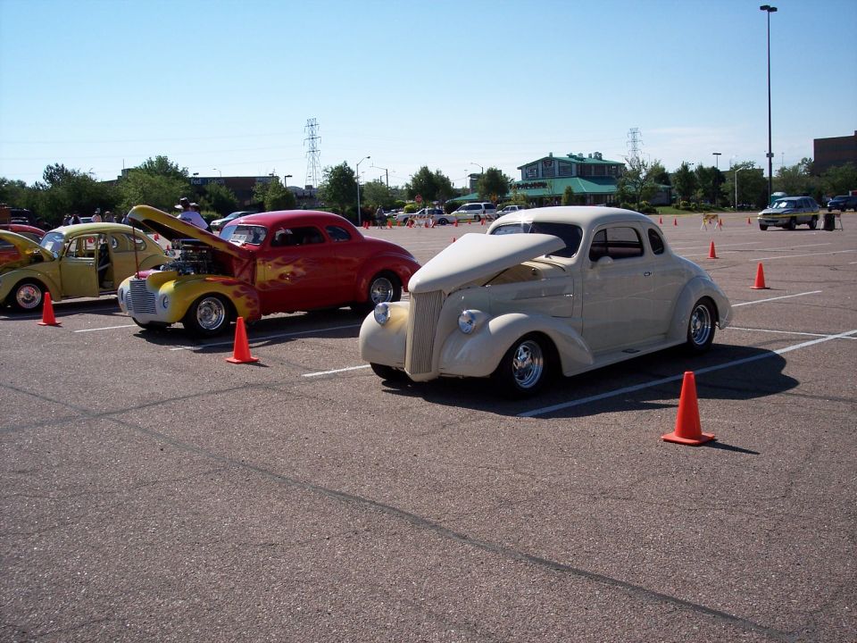 cream-colored coupe with hood up, red coupe with flames, yellow beetle in parking lot