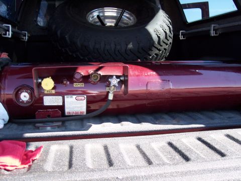 1972 Ford Ranchero - LP gas tank with connections for fill, vapor, and liquid, stored in the bed of a pickup truck.