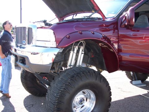 1972 Ford Ranchero - A man observes a heavily modified pickup truck custom flame graphics and an elevated suspension system.