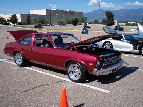 1972 Ford Ranchero - A red 1975 Chevrolet Nova coupe is displayed with its hood and trunk open at an outdoor event.