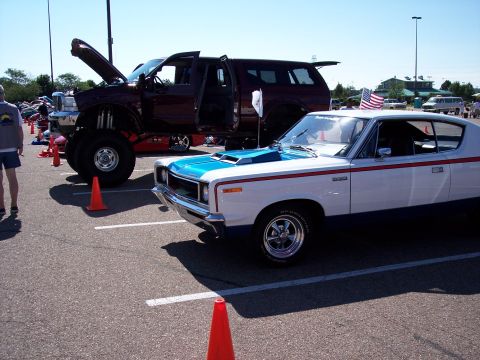1972 Ford Ranchero - A white and blue 1970s AMC Hornet is parked next to a lifted truck at a car show.