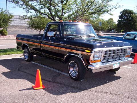 1972 Ford Ranchero - A black Ford pickup truck with chrome accents and distinctive side stripes is parked outdoors.