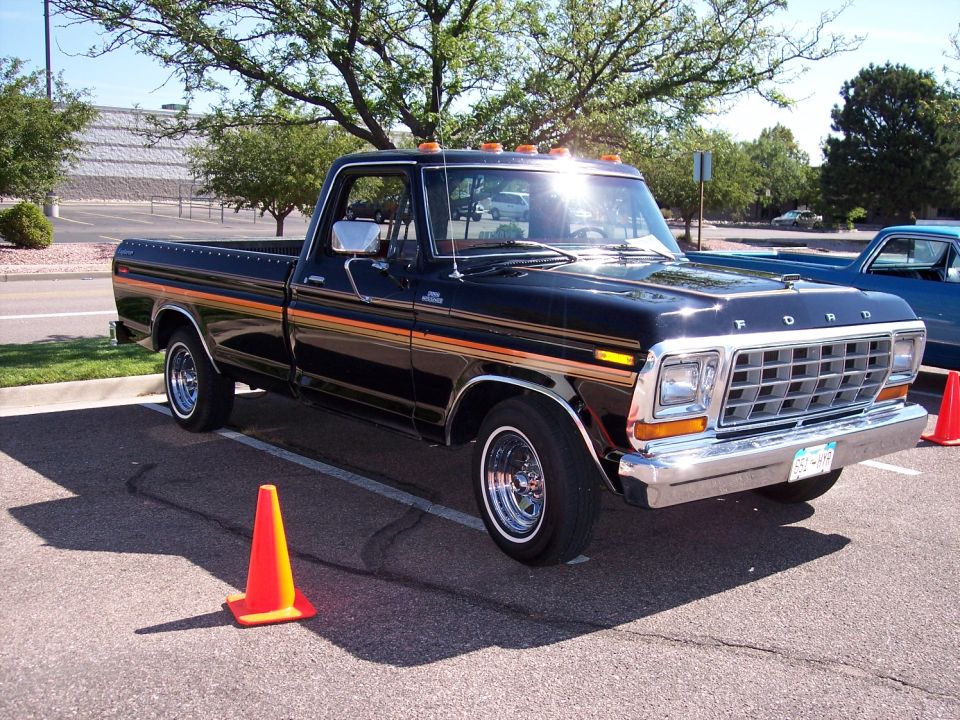 Black Ford pickup truck with orange and gold side stripes parked in a lot