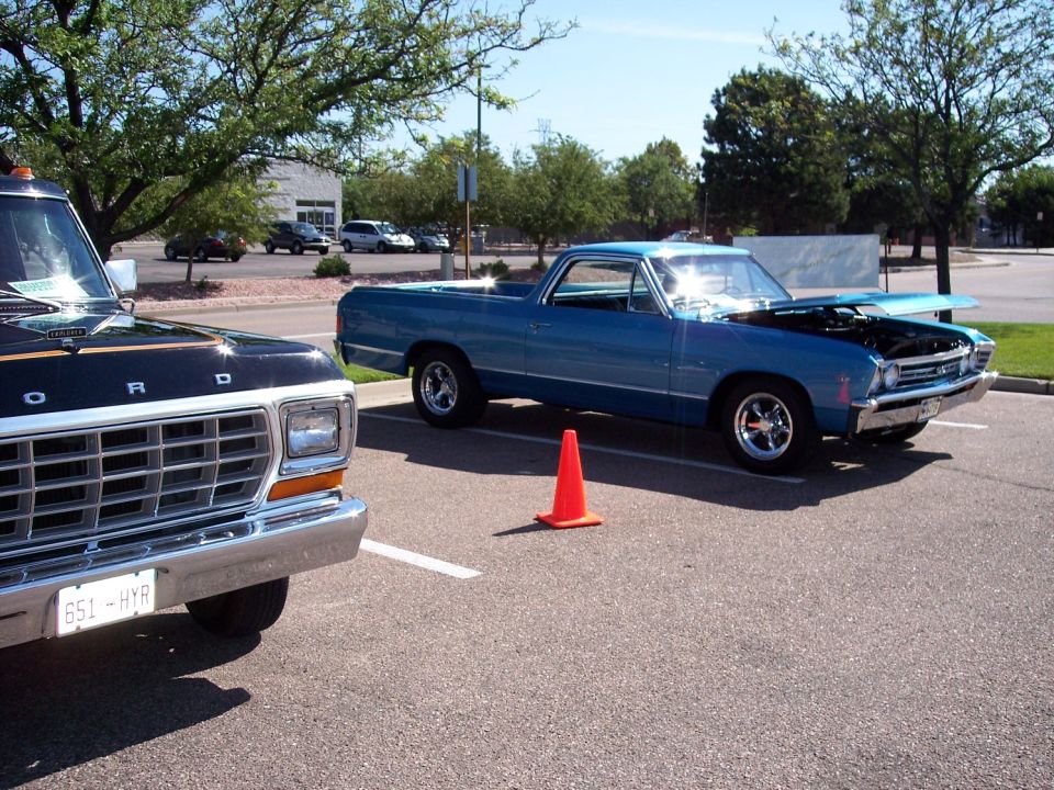 Blue 1968 Ford Ranchero with hood open, parked next to a black Ford truck