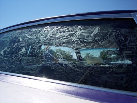 1972 Ford Ranchero - The side window of a car features intricate etched artwork with a woman's face and brick wall patterns.