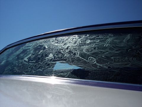 1972 Ford Ranchero - A car window displays an intricate etching of multiple vehicles and brick patterns against a clear blue sky.