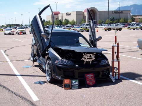 1972 Ford Ranchero - A modified black sedan is displayed with its doors and hood open, accompanied by trophies and awards.
