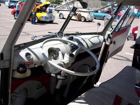 1972 Ford Ranchero - The interior of a classic van is shown, a distinctive steering wheel and dashboard. Other vehicles are visible in the background.