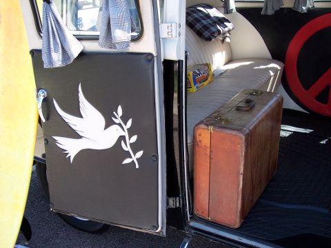 1972 Ford Ranchero - Vintage van interior features a peace sign, a leather suitcase, and a dove decal on the door.