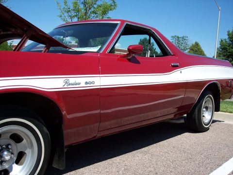 1972 Ford Ranchero - A red 1970s Ford Ranchero 500 with a white stripe and open hood is parked on asphalt under a clear blue sky.