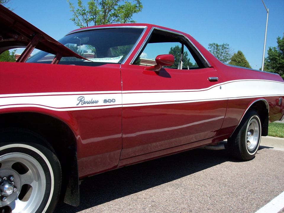 Red 1970s Ford Ranchero 500 with white side stripe, hood open, parked outdoors