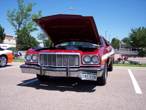 1972 Ford Ranchero - A red 1972 Ford Ranchero is parked with its hood open, displaying its grille and front end.