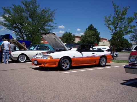 1972 Ford Ranchero - White and orange 1987 Ford Mustang convertible on display at a car show.
