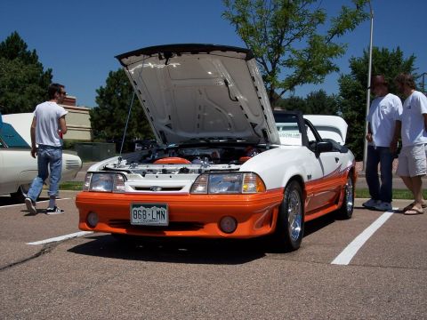 1972 Ford Ranchero - A white and orange Ford Mustang convertible is displayed with its hood open at an outdoor event.