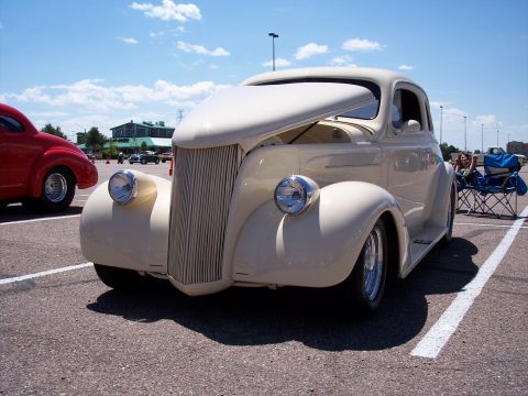 1972 Ford Ranchero - A cream-colored coupe with its hood open is parked at an outdoor event, with a red car visible to the left.