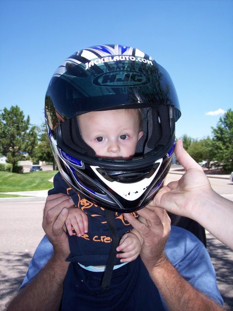 1972 Ford Ranchero - A baby is placed inside a motorcycle helmet, with hands holding the helmet and baby.