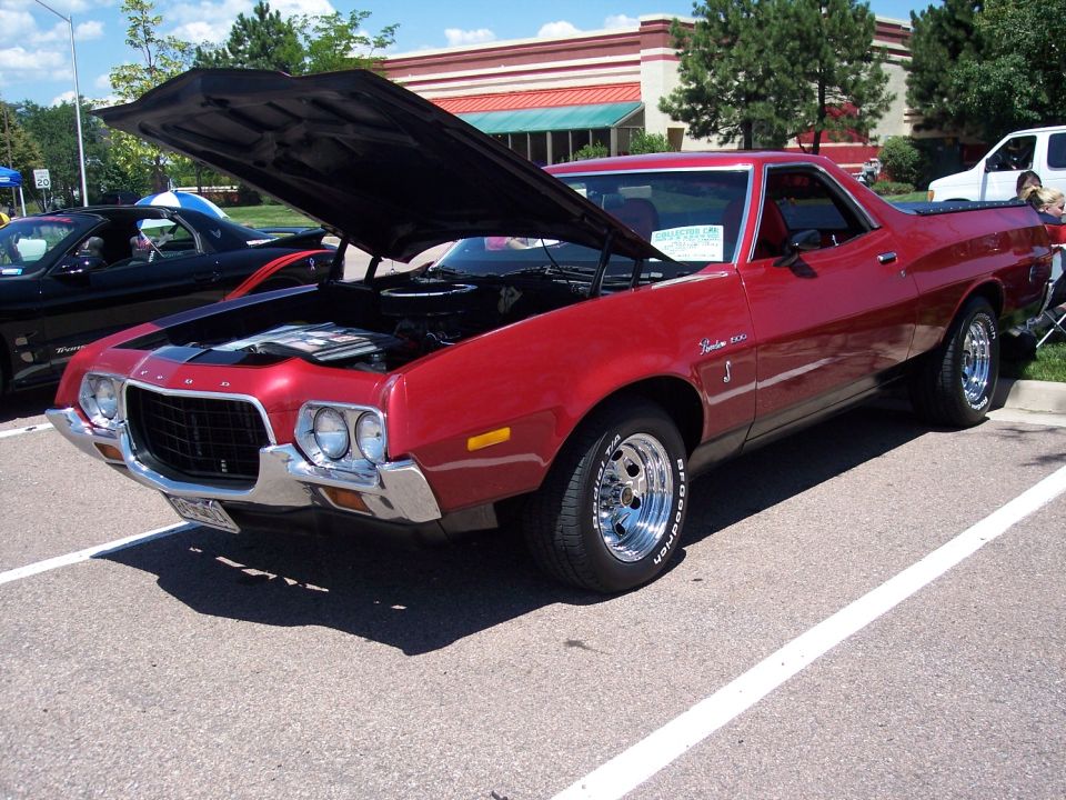 Red 1972 Ford Ranchero with hood open, chrome wheels, and BFGoodrich tires parked at a car show