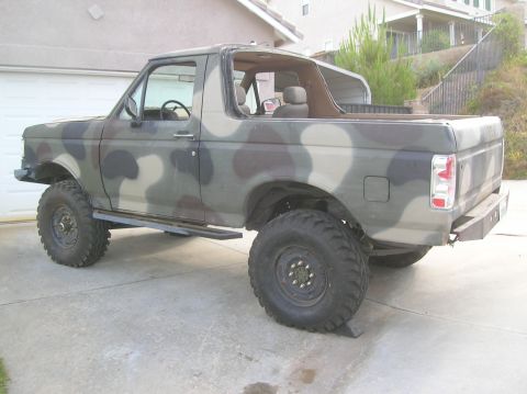 1985 Ford Bronco - This Ford Bronco features a camouflage paint scheme and aftermarket off-road modifications.