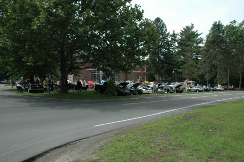 2000 Ford Mustang - A variety of vehicles are on display at an outdoor car show, with spectators mingling among them.