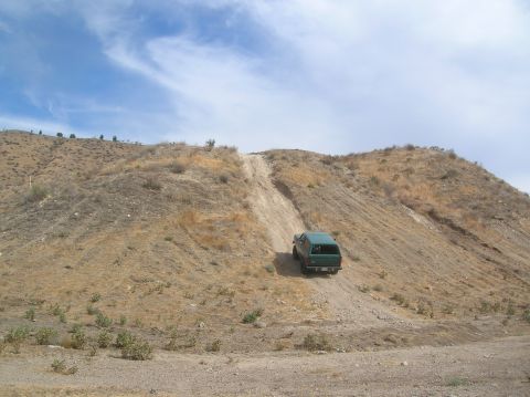 1985 Ford Bronco - SUV navigates a challenging off-road incline on a dry, arid hillside.