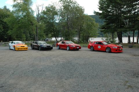 2000 Ford Mustang - A group of Ford Mustangs are parked in a scenic location by a body of water.