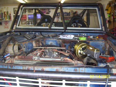 1978 Ford Bronco - The engine bay of a Ford Bronco is shown with a roll cage and racing seats visible through the windshield.