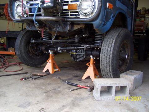 1978 Ford Bronco - The front end of a blue 1978 Ford Bronco is elevated on jack stands for maintenance.