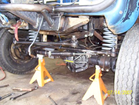 1978 Ford Bronco - The front axle and suspension of a 1978 Ford Bronco are visible, supported by jack stands.
