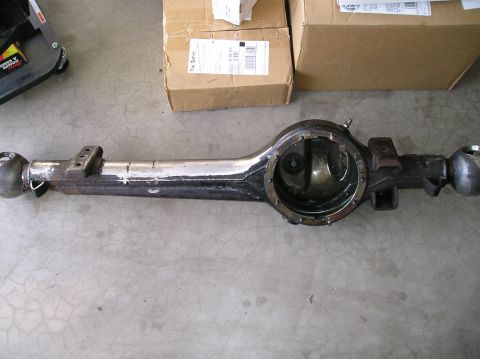 1986 Toyota Hilux - A stripped solid front axle housing lying on a garage floor, third member removed to expose the empty differential bore and ring-gear openi…