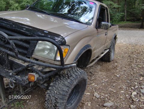 1978 Ford Bronco - A tan pickup truck with off-road tires and a bull bar is seen on a dirt road.