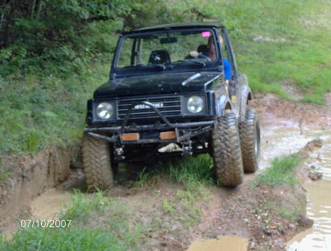 1978 Ford Bronco - This off-road vehicle navigates a challenging muddy path with water obstacles.