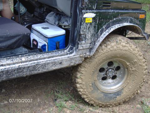 1978 Ford Bronco - The interior of a mud-covered off-road vehicle is visible, along with its side fender and tire.