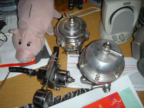 1995 Mazda MX-6 - Automotive turbocharger components and a stuffed pig are arranged on a desk with various documents.