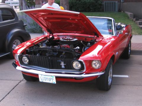 1989 Ford Mustang - A red 1969 Ford Mustang convertible is displayed with its hood open, revealing the engine bay.
